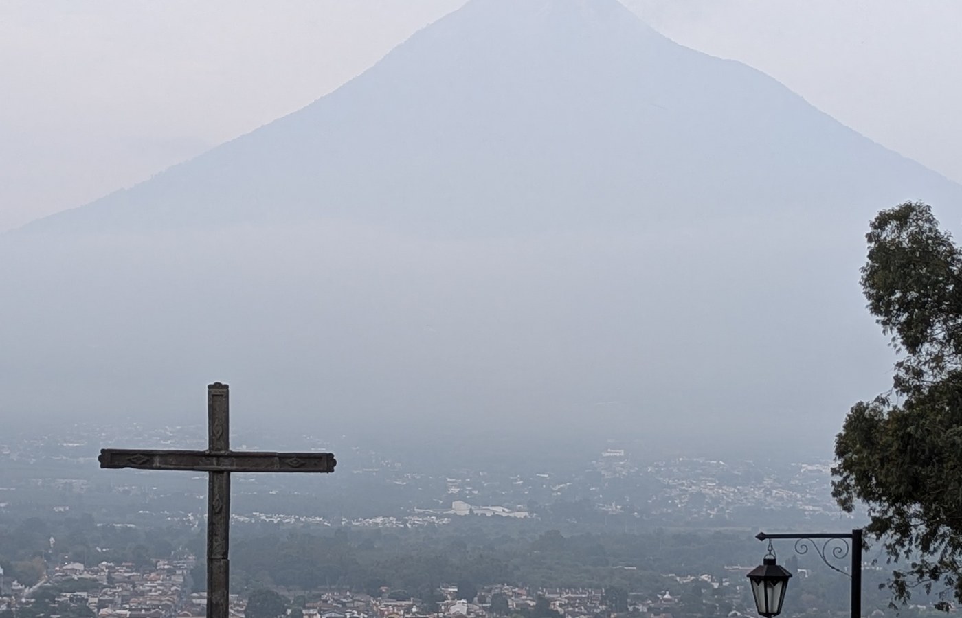 A cross overlooking Antigua with a volcano rising in the distance